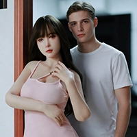 曲線美の体と長い黒髪を持つリアルな日本のセックス人形が、モダンなインテリアの中で男性の所有者と一緒にポーズをとっています。